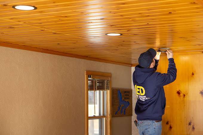 Electrician installing recessed ceiling light fixture in residential home