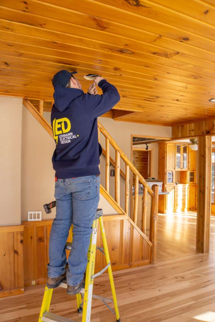 Electrician on a ladder working on wiring in a residential ceiling