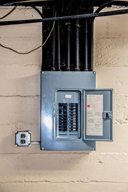 Breaker panel with its door open on a painted block basement wall