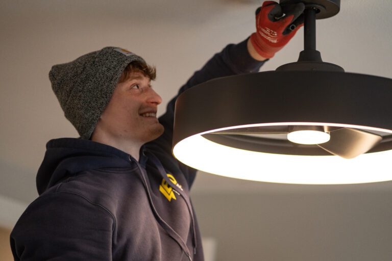 Lehmann electrician installing a black ceiling fan with a built-in LED light ring