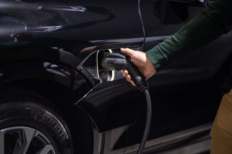 Person plugging EV charging cable into black electric vehicle's charging port
