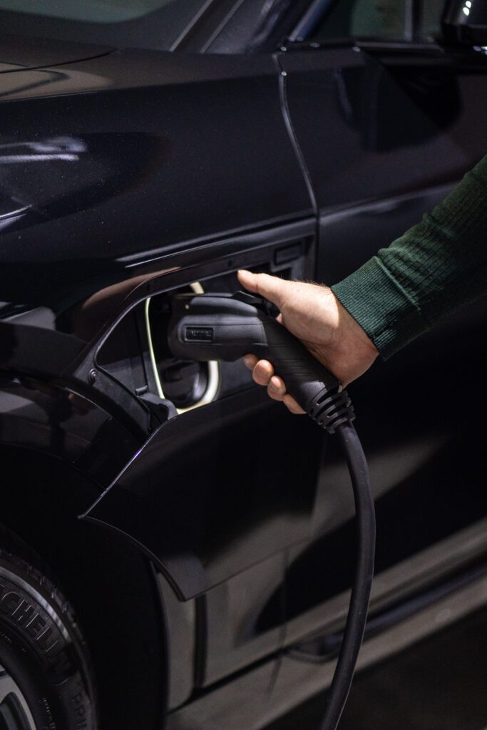 Person plugging EV charging cable into black electric vehicle's charging port