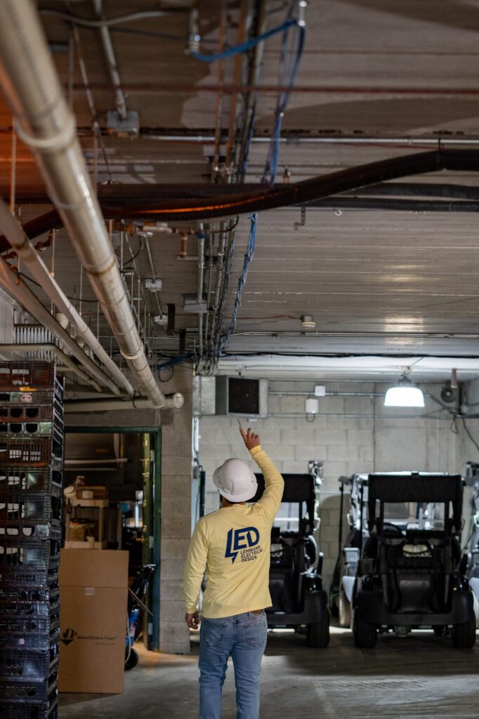 Lehmann Electrical technician inspecting overhead conduit in commercial warehouse