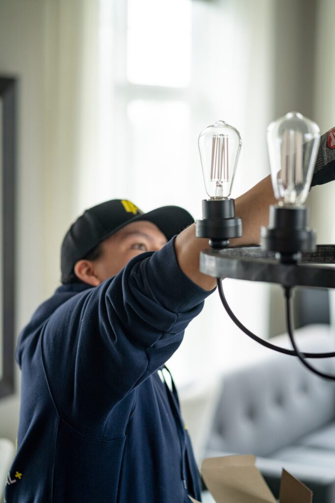 Electrician installing vintage Edison filament bulbs in a ceiling fixture