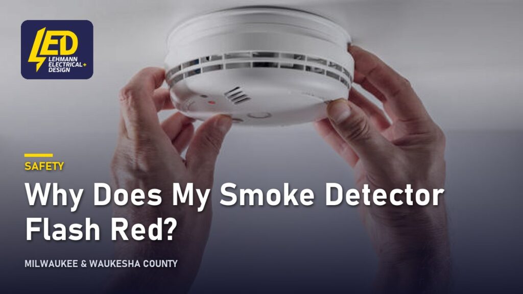 Hands installing a white circular smoke detector into a ceiling, titled Why Does My Smoke Detector Flash Red?